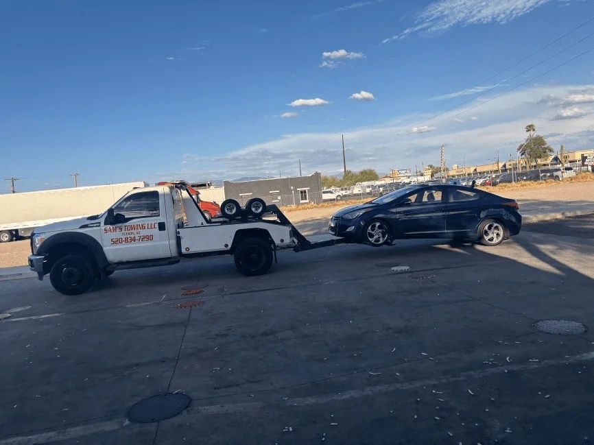 Sedan receiving a jumpstart from a Sam's Towing service truck in Tucson
