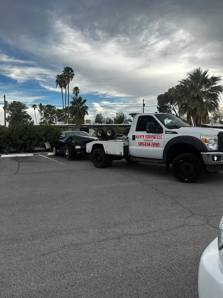 Tow truck assisting a vehicle with a flat tire in a Tucson parking lot